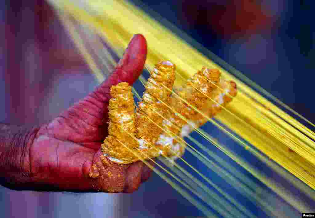 A worker applies color to strings which will be used to fly kites, in Ahmedabad, India.