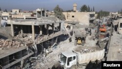 FILE - Residents inspect damage at a site hit by one of three explosive trucks in the town of Tel Tamer, Syria, Dec. 11, 2015. 