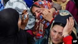 An unidentified relative is comforted by Kashmiri villagers as she grieves near the dead body of Sarjeel Sheikh, a civilian who was shot during a protest near the site of gunbattle in Khudwani village, south of Srinagar, Indian controlled Kashmir, April. 11, 2018. 