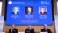 تصویر برندگان نوبل اقتصاد بر روی تابلویی پشت سر اعضای کمیته علوم نوبل.