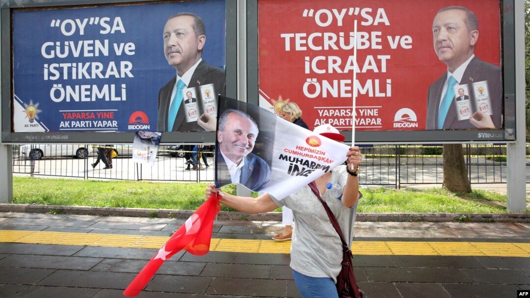 Seorang pendukung kandidat presiden Turki dari partai oposisi utama, Muharrem Ince dari Partai Rakyat Republik, melambaikan bendera saat berjalan melewati poster-poster kampanye petahana, Presiden Recep Tayyip Erdogan, dalam pawai pemilu di Ankara, 22 Juni 2018.
