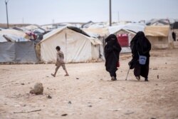 FILE - Women walk in the al-Hol camp that houses some 60,000 refugees, including families and supporters of the Islamic State group, many of them foreign nationals, in Hasakeh province, Syria, May 1, 2021.