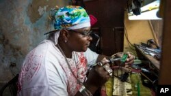 Jeweler and electronics technician Gabriel La O repairs a phone inside a government store where he rents work space in Havana, May 24, 2016. Cuba says it will legalize small and medium-sized private businesses, adding to the Communist Party’s master plan for social and economic development. 