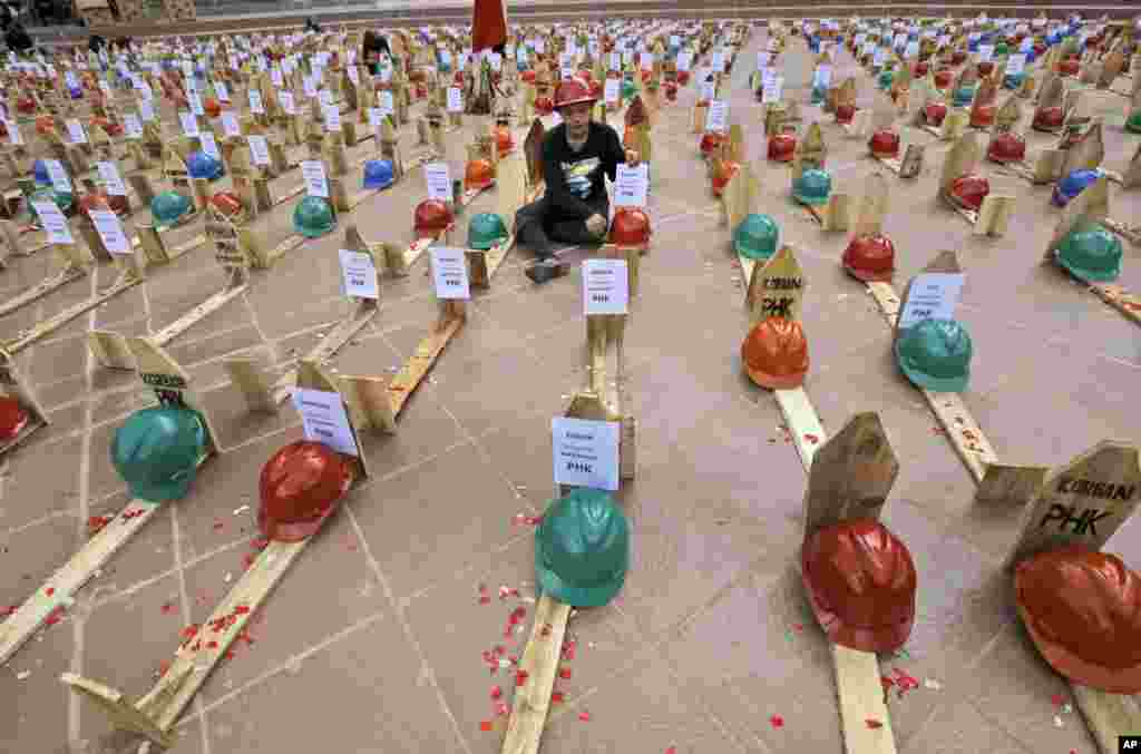 An activist of National Solidarity of Mine Workers sits among mock graves of miners during a protest against the government&#39;s plan to ban raw mineral exports that will take effect this month, in Jakarta, Indonesia.