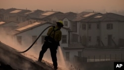 Firefighter Tylor Gilbert puts out hotspots while battling the Silverado Fire, Oct. 26, 2020, in Irvine, Calif. 