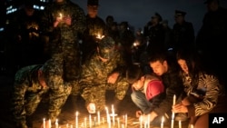 Foto ilustrasi yang menunjukkan tentara dan warga sipil menyalakan lilin untuk mengenang para tentara yang tewas dalam serangan yang dilakukan angkatan Bersenjata Revolusioner Kolombia (FARC). Acara digelar di Bogota, Kolombia, pada 9 Desember 2022. (Foto: AP/Ivan Valencia)