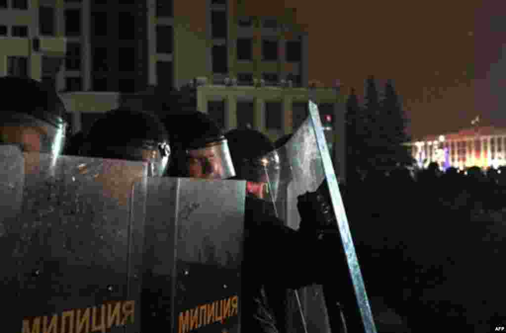 Riot police officers block the road near the government building during an opposition rally in Minsk, Berlarus, early Monday, Dec. 20, 2010. Thousands of opposition supporters in Belarus tried to storm the main government building to protest what the oppo