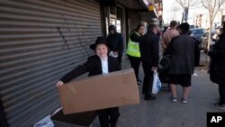 FILE - A boy carries a box of matzos for Passover that he picked up from his synagogue in the Brooklyn borough of New York, March 26, 2020. The coronavirus has forced Jewish families to limit the celebratory Passover meals known as Seders.