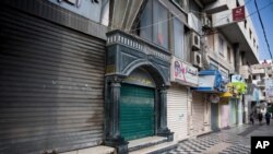 Palestinians walk next to closed shops in Gaza City, Tuesday, June 25, 2019, during a general strike against this week's economic conference in Bahrain that will kick off the Trump administration's plan for Mideast peace. 