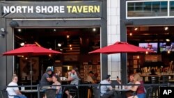 People gather at the North Shore Tavern in Pittsburgh, June 28, 2020. In response to the recent spike in COVID-19 cases, health officials are ordering all bars and restaurants in Allegheny County to stop the sale of alcohol for on-site consumption.