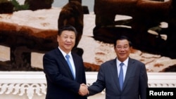 Chinese President Xi Jinping and Cambodian Prime Minister Hun Sen shake hands as they pose for a picture at the Prime Minister's office in Phnom Penh, October 13, 2016.