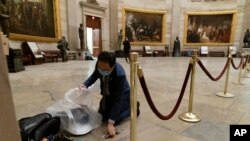 Rep. Andy Kim, D-N.J., cleans up debris and personal belongings strewn across the floor of the Rotunda after protesters stormed the Capitol on Jan. 6, 2021, in Washington.