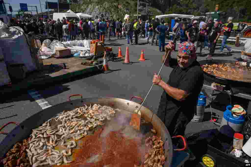 یک مرد حین پختن غذا در جریان اعتراض دهقانان که شاهراه میان فرانسه و اسپانیا را مسدود کردند &nbsp;