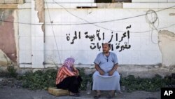 A Syrian couple, who fled their home, sits on the side of the road as they take refuge at the Bab Al-Salameh border crossing in hopes of entering one of the refugee camps in Turkey, near the Syrian town of Azaz, August 23, 2012.