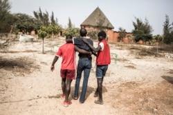 FILE - A homeless young man, who is thought to be suffering from malnutrition, is helped to the clinic in a quarantined area at a refuge for newly arrived street children outside Dakar, April 10, 2020.