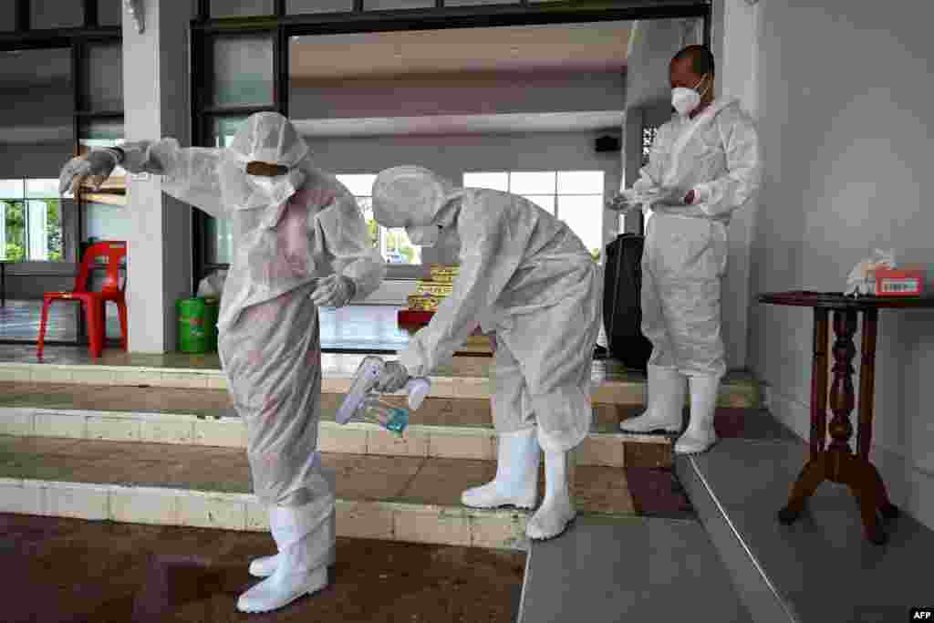 Buddhist monks disinfect themselves after performing cremation duties for COVID-19 coronavirus victims, at Wat Chin Wararam Worawihan in Bangkok, Thailand.