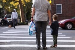 FILE - Dough Hassebroek walks his son Felix to Ardor School in Brooklyn, New York, Sept. 21, 2020.