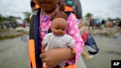 Una niña venezolana sostiene su muñeca al disponerse a embarcar en un bote en Necoclí con destino a Acandi, ambas localidades en Colombia, el 13 de octubre de 2022.