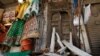 A street vendor waits for customers next to a damaged main door of a Hindu temple, that was vandalized by a group of assailants, in Rawalpindi, Pakistan, Monday, March 29, 2021. Assailants in Pakistan damaged the nearly century-old Hindu temple in…