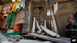 A street vendor waits for customers next to a damaged main door of a Hindu temple, that was vandalized by a group of assailants, in Rawalpindi, Pakistan, March 29, 2021.