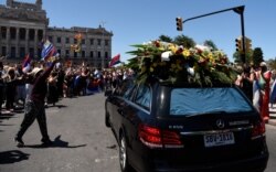 Dolientes ondean banderas al paso de la carroza funeraria del expresidente de Uruguay, Tabaré Vázquez, cuando pasaba por el Congreso de camino al cementerio en Montevideo, el domingo 6 de diciembre de 2020.