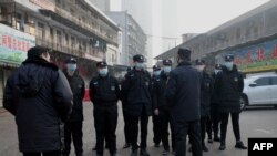 Security guards stand in front of the closed Huanan wholesale seafood market, where health authorities say a man who died from a respiratory illness, had purchased goods from, in the city of Wuhan, Hubei province, China, Jan. 12, 2020.