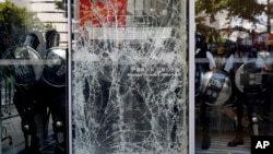 Полицейские блокируют разбитую демонстрантами стеклянную дверь. Гонконг, 1 июля 2019 г.