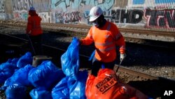 Workers bag cardboard and other discarded items at a Union Pacific railroad site on Jan. 20, 2022, in Los Angeles. 