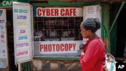 Seorang pejalan kaki berjalan melewati sebuah warung internet di wilayah miskin Kibera di Nairobi, Kenya, pada 29 September 2021. (Foto: AP/Brian Inganga)