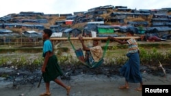 Rohingya refugees carry an old woman in a sling near Balukhali makeshift refugee camp in Cox's Bazar, Bangladesh, Sept. 13, 2017. 