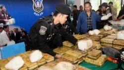 Thai policemen arrange packages of methamphetamine on a table before a press conference in Bangkok, Thailand