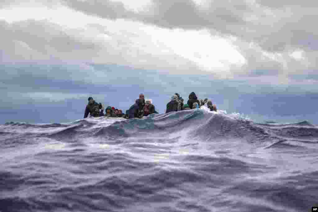 Men from Morocco and Bangladesh react on an overcrowded wooden boat, as aid workers of the Spanish NGO Open Arms approach them in the Mediterranean Sea, international waters, off the Libyan coast.