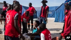 Les éléments de la Croix rouge assistent Fatou Jeng, au centre, après sa traversée à la frontière gambienne avec son enfant, dans le village de Karanga, Sénégal, 19 janvier 2017.