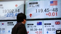 FILE - A man checks an electronic board for exchange rates in Tokyo, Japan, May 7, 2015. 