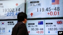 FILE - A man checks an electronic board for exchange rates in Tokyo, Japan.