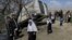 FILE - Schoolgirls walk past a damaged minibus after it was hit by a bomb blast in the Bagrami district of Kabul, Afghanistan.