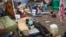 FILE - A sick displaced man lies asleep on a bed while a mother bathes her son and keeps an eye on her other child in the United Nations camp in Juba, South Sudan, Feb. 12, 2014. 