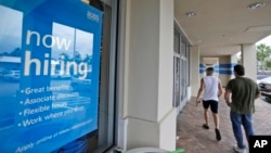 FILE - Shoppers walk past a now hiring sign at a Ross store in North Miami Beach, Florida, May 16, 2014.