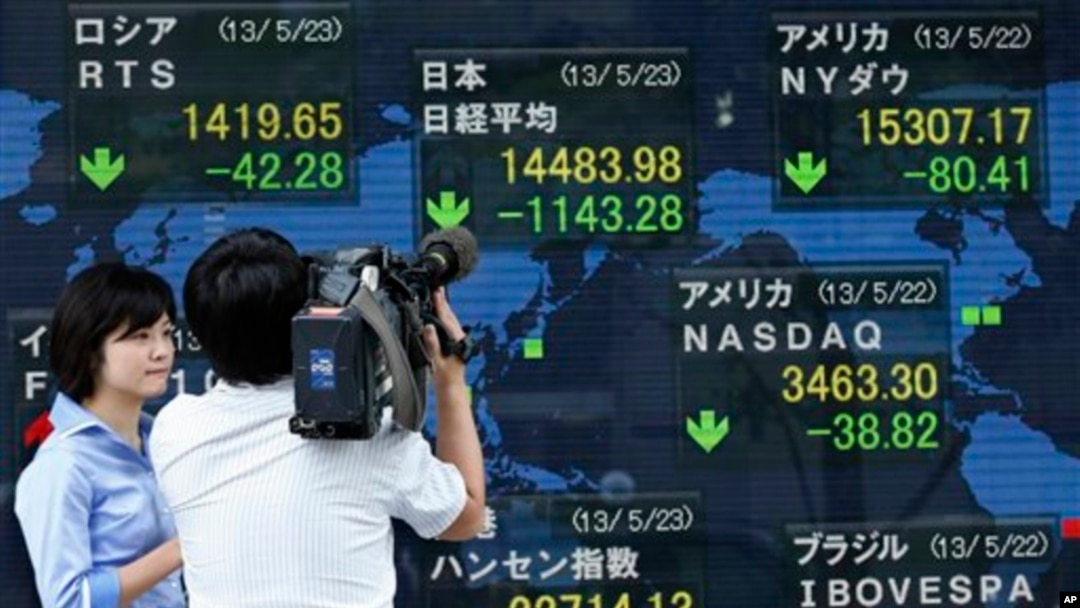 Seorang juru kamera tengah menyoroti indikator elektronik yang terpampang di luar gedung sebuah perusahaan sekuritas di Tokyo (23/5). Indeks Nikkei Jepang turun tajam sebanyak 7,3 persen dan berakhir dengan 1.143 poin lebih rendah dibandingkan saat pembukaan lantai bursa di pagi harinya.