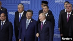 ARCHIVO - El presidente ruso, Vladimir Putin, habla con el mandatario chino, Xi Jinping, mientras otros participantes en la reunión de formato BRICS Plus posan para una foto familiar durante la cumbre BRICS en Kazán, Rusia, el 24 de octubre de 2024