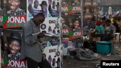 Un homme lis un journal devant une affiche de campagne électorale à Lagos, Nigéria, lundi 30 mars 2015.