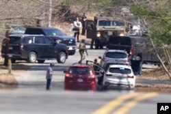 Members of law enforcement assemble on a road, Thursday, April 13, 2023, in Dighton, Mass., near where FBI agents converged on the home of a Massachusetts Air National Guard member who has emerged as a main person of interest in the disclosure of highly classified military documents on the Ukraine.