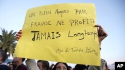 A Tunisian demonstrator holds a sign that says "things acquired fraudulently never last long" during a protest against the Islamist Ennahda movement in Tunis, October 26, 2011.