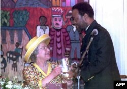 FILE - British Queen Elizabeth II looks up to Zulu King Zwelithini as he presents her a replica of a cup given to King Cetshwayo by Queen Victoria in 1882, here at a ceremonious luncheon in Durban, March 25, 1995.