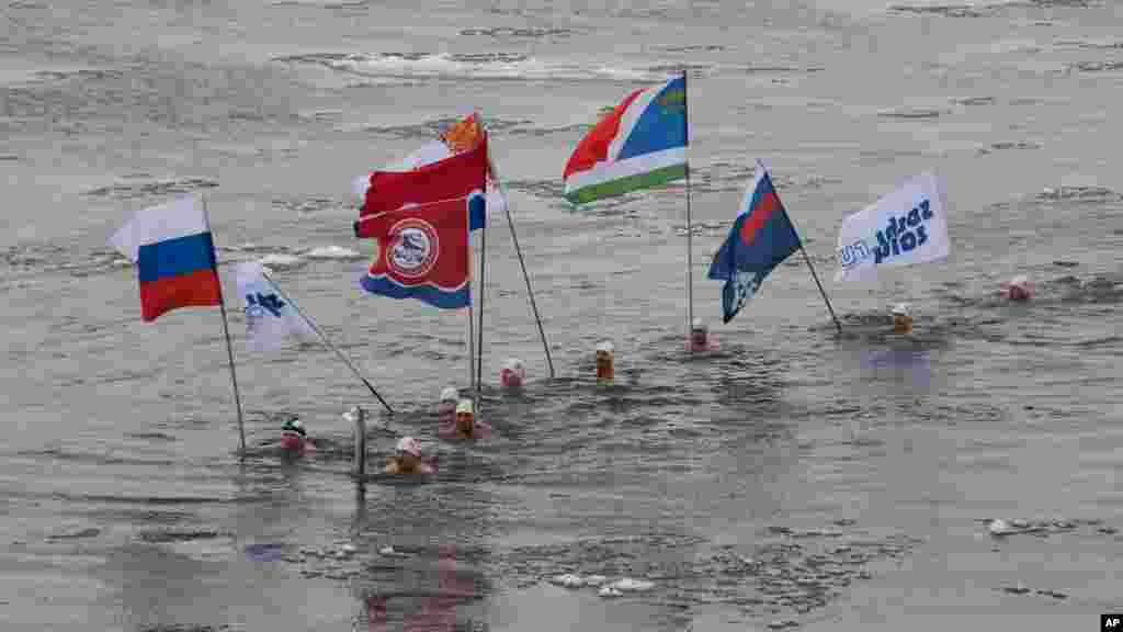 Pembawa obor Olimpiade musim dingin Socchi 2014, Alexander Brylin, bersama para perenang lainnya membawa obor olimpiade melintasi sungai Amur di kota Blagoveshchensk, Rusia timur. 