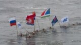 In this photo provided by Olympictorch2014.com torch bearer Alexander Brylin, with other ice swimmers, swims with Olympic torch during the torch relay in the Amur River in Blagoveshchensk, Russia&#39;s Far East.