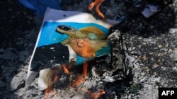 FILE - Protesters burn an illustration of U.S. President Donald Trump being hit with shoes, in the West Bank city of Ramallah, Aug. 24, 2017.