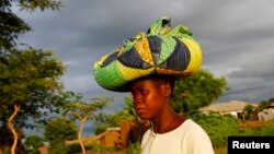 Rain clouds loom as Malawian subsistence farmer Louise Abele carries maize she has bought to feed her family near the capital Lilongwe, Malawi, Jan. 31, 2016. 