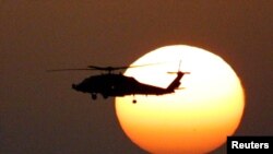 Un helicóptero del ejército estadounidense vuela frente a una puesta de sol, en algún punto del Océano Índico, el 28 de noviembre de 2001, poco después de que comenzara la guerra en Afganistán.