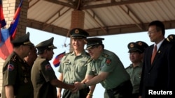 FILE - Cambodian Defense Minister Tea Banh, second left, shakes hands with a Chinese army adviser during a graduation ceremony at the Army Institute in Kampong Speu province, March 12, 2015. 